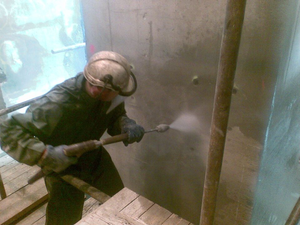 Pracovník čistí betonovou stěnu vysokotlakým vodním paprskem